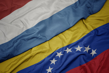 Fototapeta premium waving colorful flag of venezuela and national flag of luxembourg.