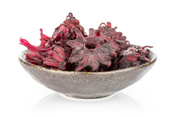 Lot of whole sweet red candied hibiscus in dark ceramic bowl isolated on white background