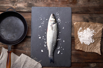 fresh whole sea bass fish on a black board
