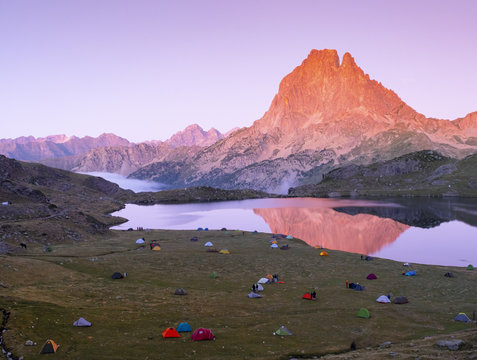 Camping tents on Lake Gentau at night with Mount Midi d'Ossau reflected on the lake, France