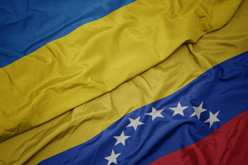 waving colorful flag of venezuela and national flag of ukraine.