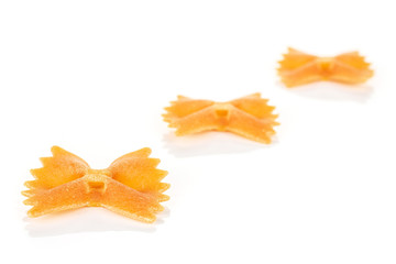 Fototapeta premium Group of three whole red uncooked farfalle isolated on white background