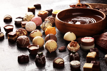 a lot of variety chocolate pralines, belgian confectionery gourmet chocolate on rustic dark background