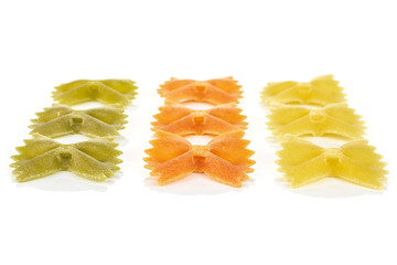 Group of nine whole red, yellow and green uncooked farfalle isolated on white background