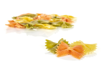 Lot of whole red, yellow and green uncooked farfalle isolated on white background