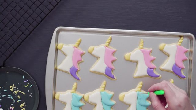 Flat lay. Decorating unicorn sugar cookies with multi-color royal icing.