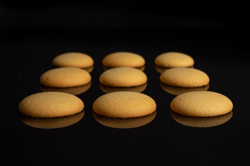 Fototapeta na wymiar Group of nine whole sweet golden sponge biscuit isolated on black glass