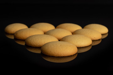 Group of ten whole sweet golden sponge biscuit isolated on black glass