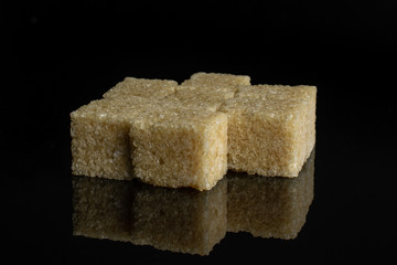 Lot of whole sweet brown sugar cube in small group isolated on black glass