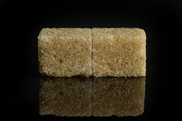 Group of two whole sweet brown sugar cube isolated on black glass