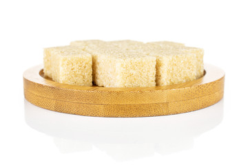 Lot of whole sweet brown sugar cube on bamboo coaster isolated on white background