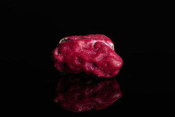 One whole purple sweet chocolate stone isolated on black glass