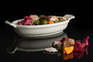 Lot of whole sweet chocolate stone small group is in the front and the rest is in white oval ceramic bowl isolated on black glass