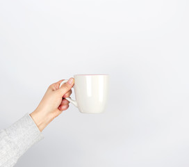 Fototapeta na wymiar gray ceramic cup in female hand on a white background