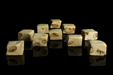 Lot of whole sweet white nougat placed symmetrically isolated on black glass