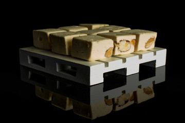 Group of nine whole sweet white nougat on white wooden pallet isolated on black glass