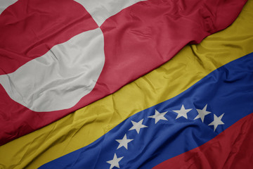 waving colorful flag of venezuela and national flag of greenland.