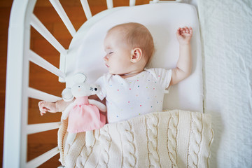 Baby sleeping in co-sleeper crib attached to parents' bed