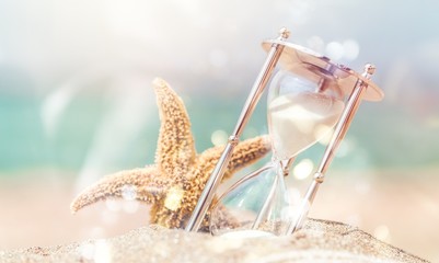 Hourglass and seastar on sandy beach