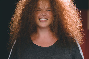 Portrait of ethnic redhead curly-haired woman with freckles.