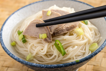 Grabbing pork slice from top of noodles.