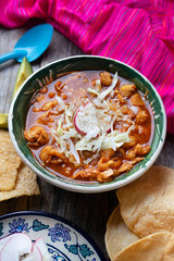 Mexican red pozole soup on wooden background