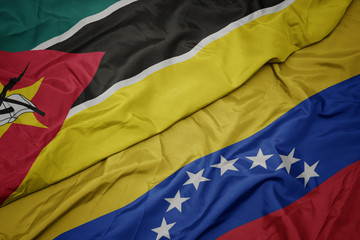 waving colorful flag of venezuela and national flag of mozambique.