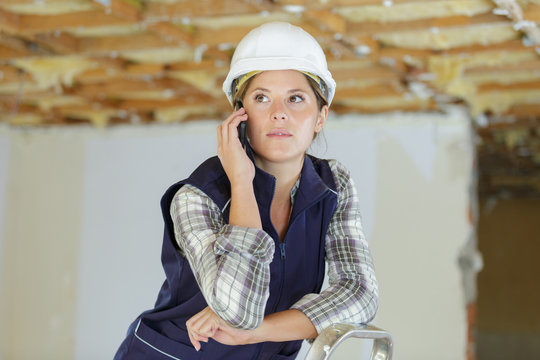 young engineer woman with safety hard hat talking on phone - Powered by Adobe
