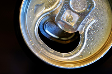 Drops of moisture on an open aluminum can with a drink. Dark background. Quenching thirst