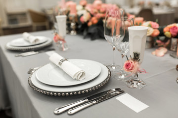 Part of stylish table setting with plate and cutlery. Nearby lies a white business card. Copy space