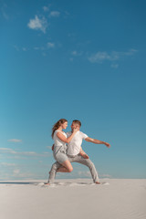 Fototapeta na wymiar Romantic couple dancing in sand desert at blue sky background.