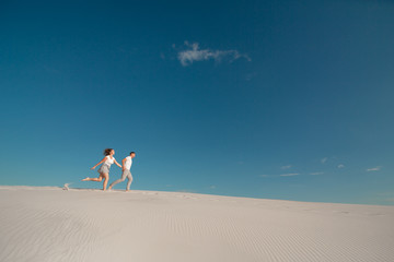 Romantic couple in love running on white sand in desert.