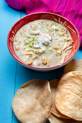 Mexican green pozole soup on blue background