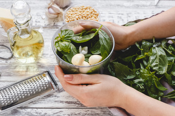The process of making pesto sauce in a blender from cheese, pine nuts, olive oil, basil, garlic on...