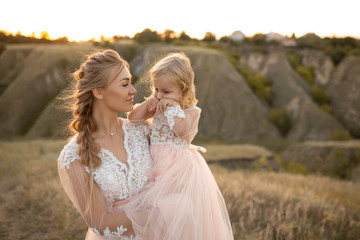 Fototapeta na wymiar Mom with daughter in pink fairy-tale dresses walk in nature. Little princess childhood