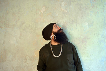 Men with huge beard and piercings looking up a wall
