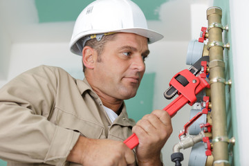 male plumber fixing water meter with adjustable wrench