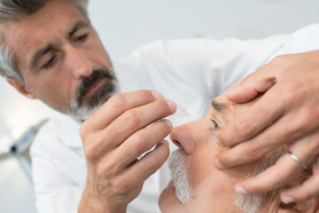 eye specialist putting eyedrops to the patients eye
