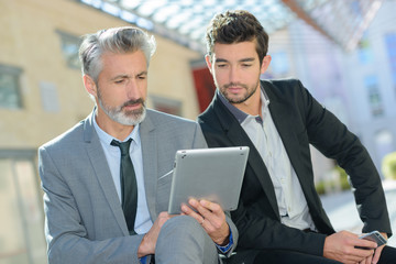 portrait of young man and senior with digital tablet outdoor