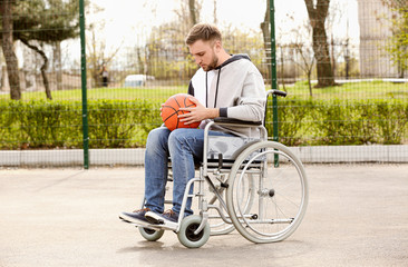 Upset man in wheelchair with ball on sports ground