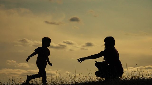 happy family mother and son outdoors silhouette concept slow motion video. little boy runs hugs mom girl. mom girl hugs takes care of her son little boy lifestyle silhouette at sunset teamwork. happy