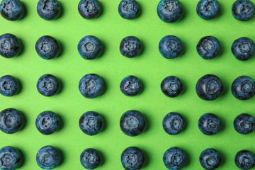 Tasty ripe blueberries on green background, flat lay