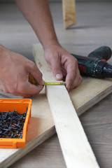 Carpenter measuring width of wooden lath 