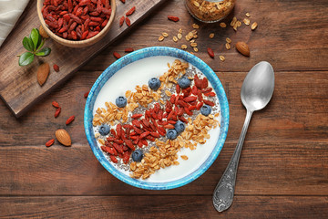 Flat lay composition of smoothie bowl with goji berries on wooden table