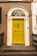 A yellow door with columns in a street of row homes in Ireland