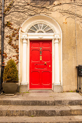 A red door with columns in a street of row homes in Ireland