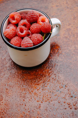 A mug of ripe Raspberries on a rustic metal background