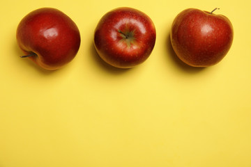 Flat lay composition with ripe juicy red apples on yellow background, space for text
