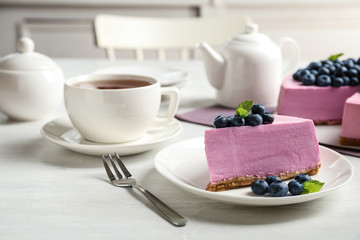 Plate with piece of tasty blueberry cake served on light table. Space for text