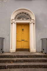 A yellow door with columns in a street of row homes in Ireland